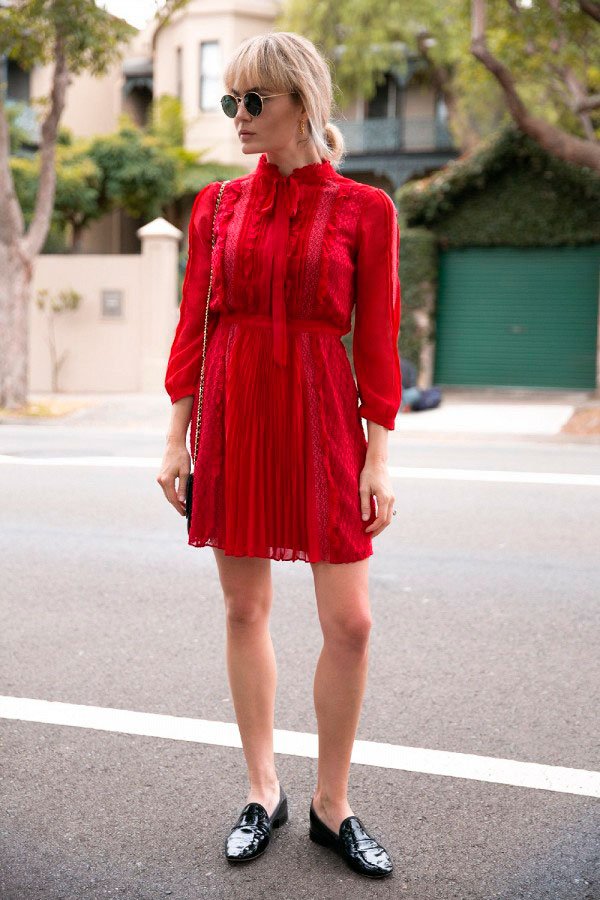 Street style look com vestido curto manga longa vermelho, sapato boyish flat preto, óculos redondo e bolsa com alça corrente.