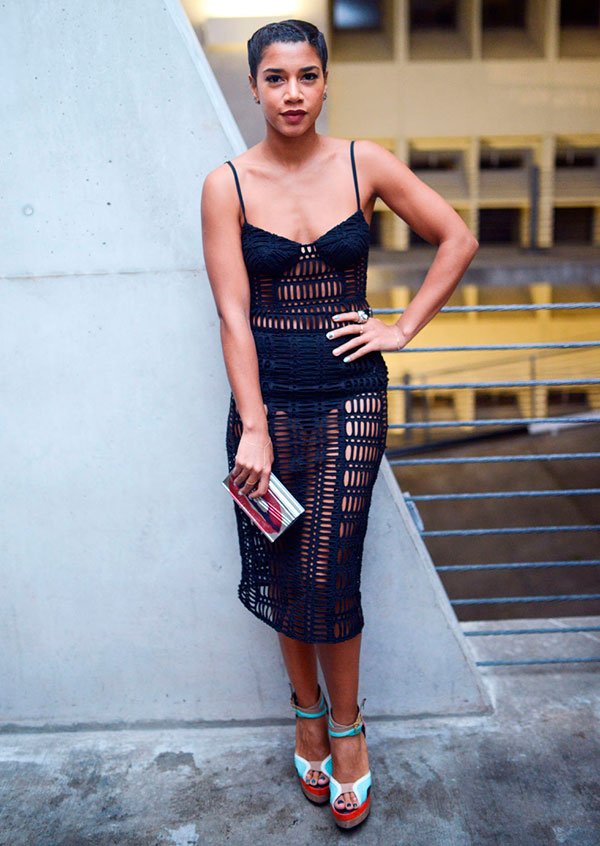 Hannah Bronfman posa pra foto em premiação com vestido rendado transparente e sandália colorida