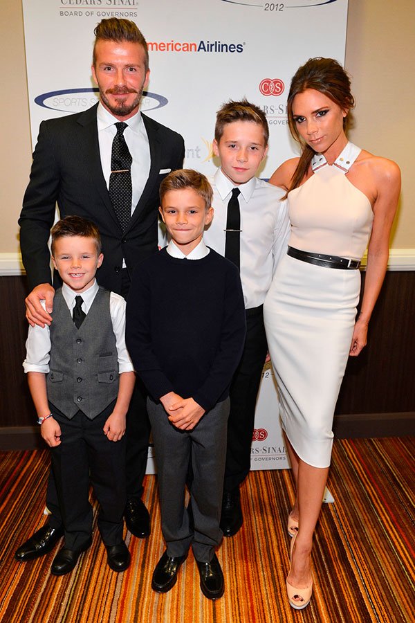 Victoria Beckham com a família toda em evento, veste vestido midi branco e peeptoe