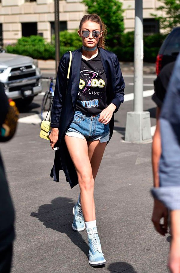 Gigi Haddis usa shorts jeans curto com tenis e blazer mais camiseta estampada