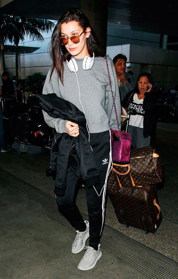 Street style look de Bella Hadid usando agasalho tracksuit Adidas com moletom cinza, calca preta, tênis e bolsa roxa