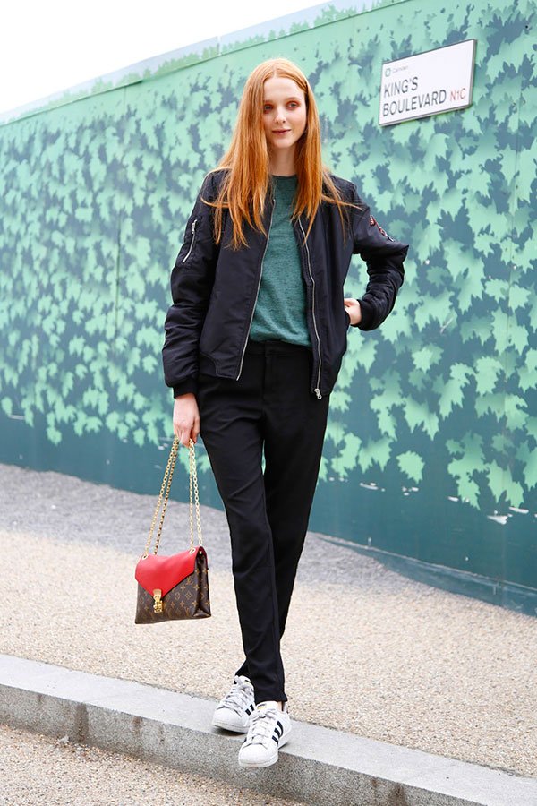 Street style look com calça alfaiataria preta, bomber jacket e tênis branco mais tshirt verde