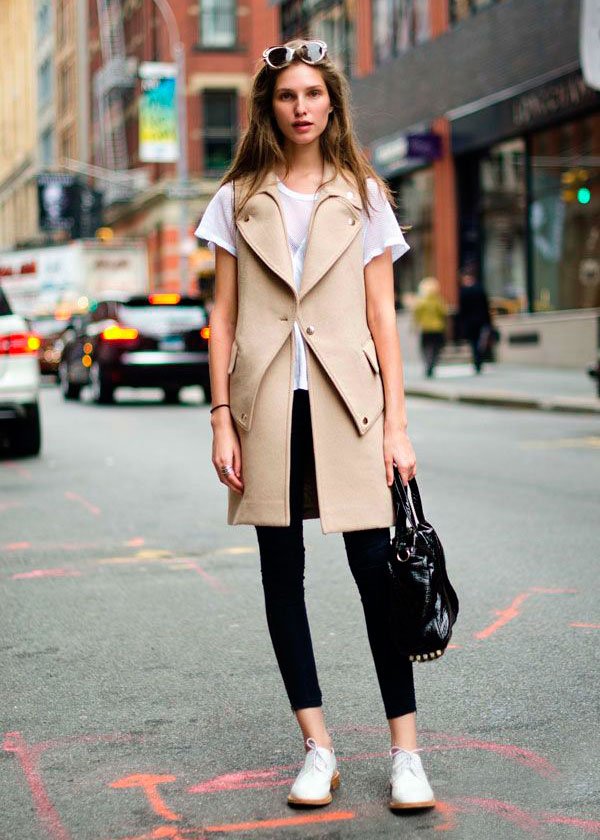 Street style look com colete longo bege, calça alfaiataria e tenis