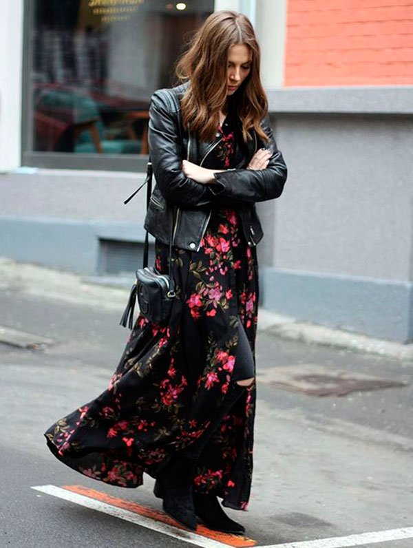 Street style look com vestido longo floral sobre calça preta e botas.