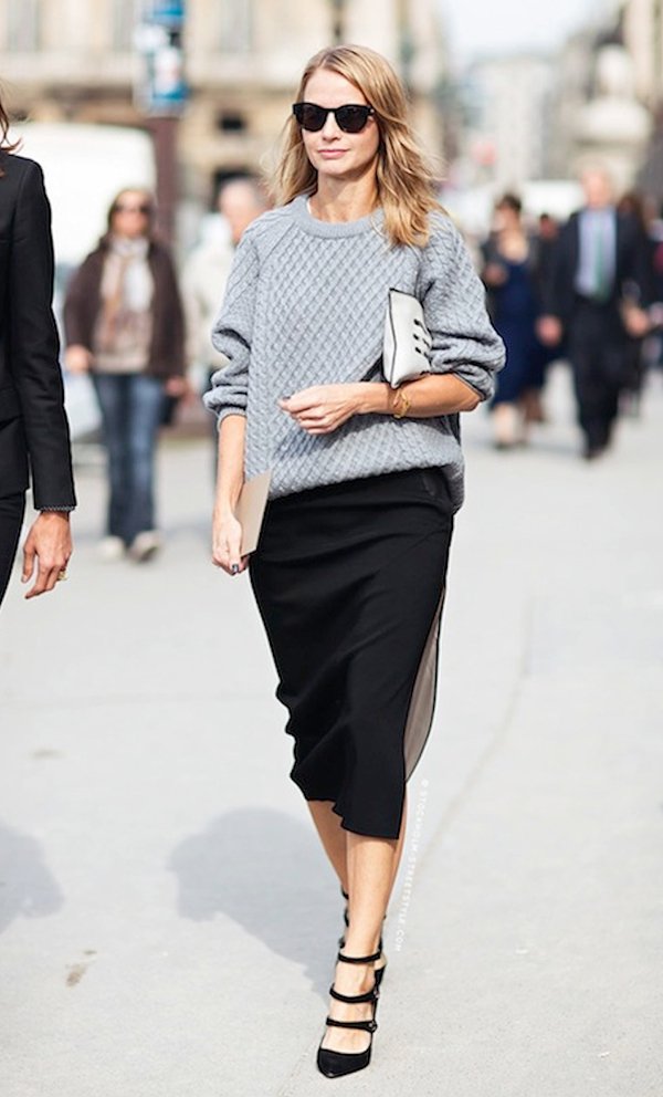 Mulher anda pelas ruas de Paris usando maxi tricot cinza mescla, saia midi preta, scarpin preto de tiras, clutch embaixo do braço e óculos escuros