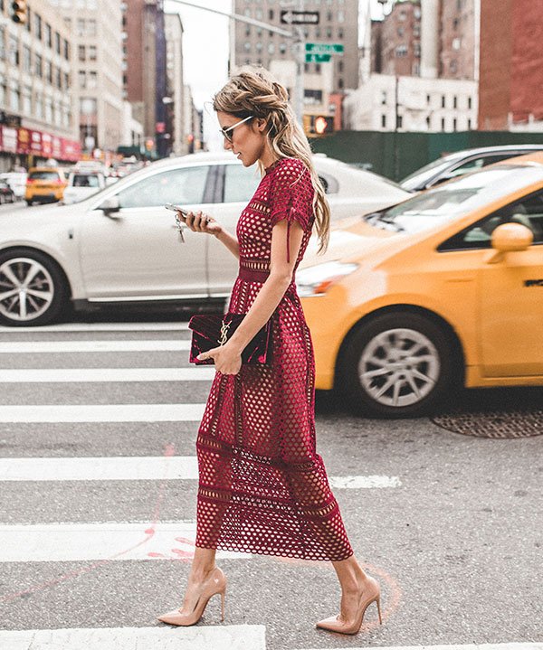 Mulher atravessa da rua de Nova York vestindo vestido midi burgundy, scarpin nude, bolsa yves saint laurent de veludo vinho