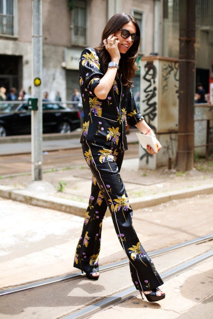 Viviana Volpicella atravessa a rua usando look todo de pijama de seda floral, salto alto preto e óculos escuros