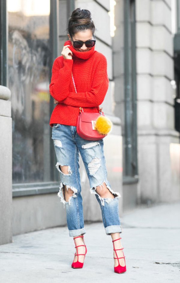 Look de street style com maxi tricot de gola alta vermelho, calça jeans destroyed, scarpin vermelho e bolsa Céline vermelha