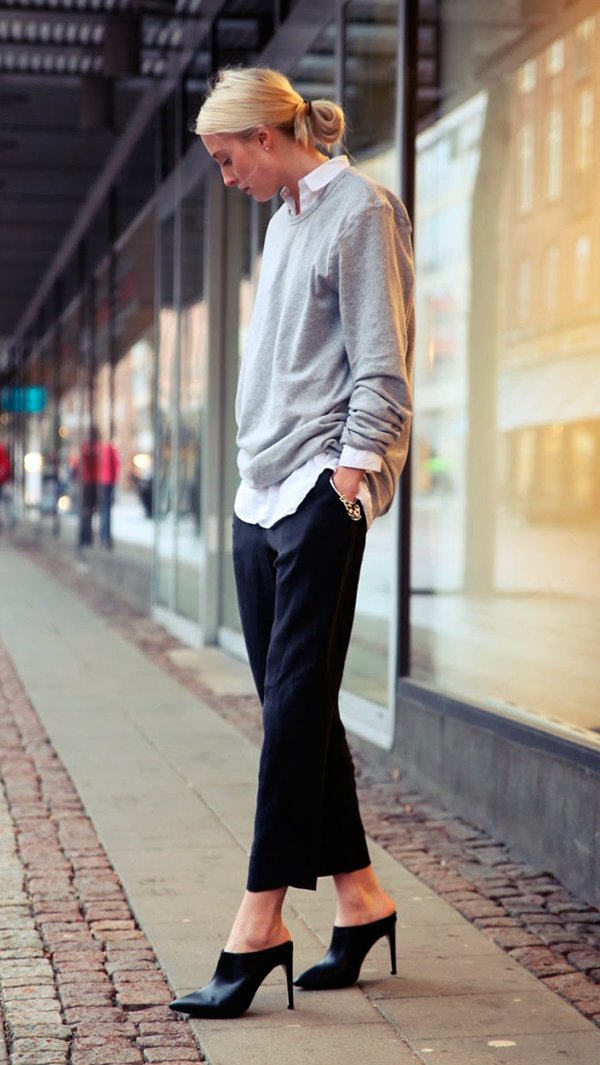 Carolyne Bessette usa look com camisa branca, tricot cinza, calça cropped preta e mule preto