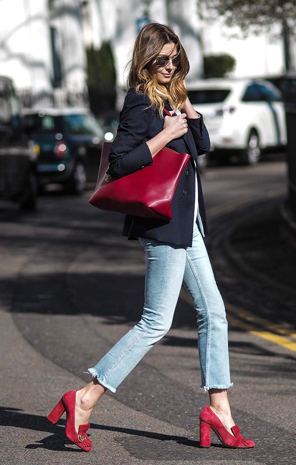 Emma Hill usa blazer azul marinho, calça jeans cropped, sapato vermelho gucci e bolsa vermelha