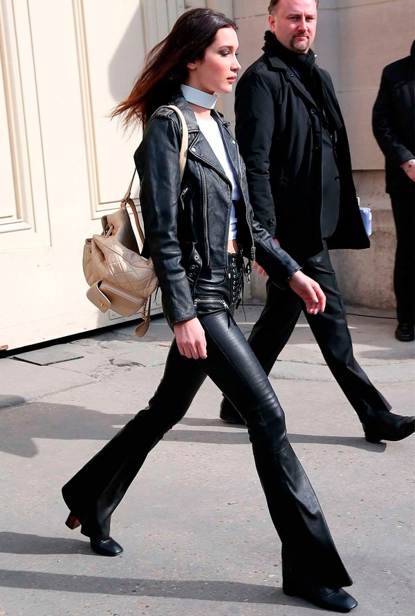 Street style look Bella Hadidi com jaqueta couro, calça resinada, botas e white choker.
