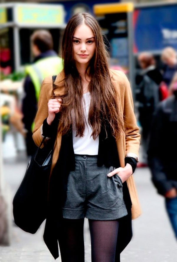 Street style look blusa branca, shorts preto e casaco caramelo.