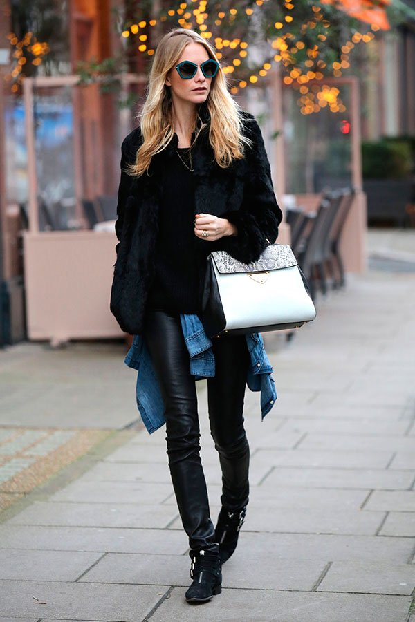 Street style look com calça de couro preta, blusa, casaco peludo maxi e botas.