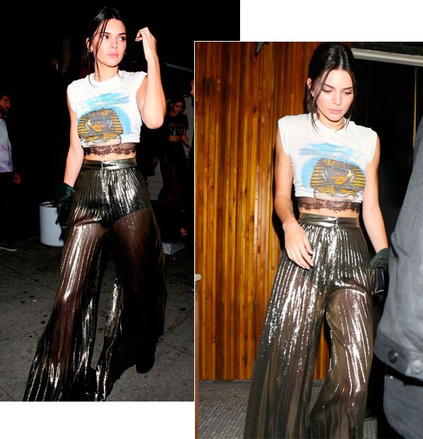 Kendall Jenner street style look com calça metálica transparente, hot pant, camiseta com top renda aparente.