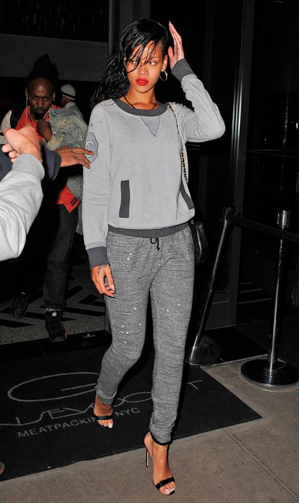Street style look Rihanna com conjunto moletom cinza, sandália de salto e batom vermelho.