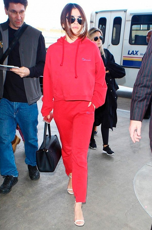 Street style look Selena Gomez com conjunto esportivo vermelho e sandália tiras.