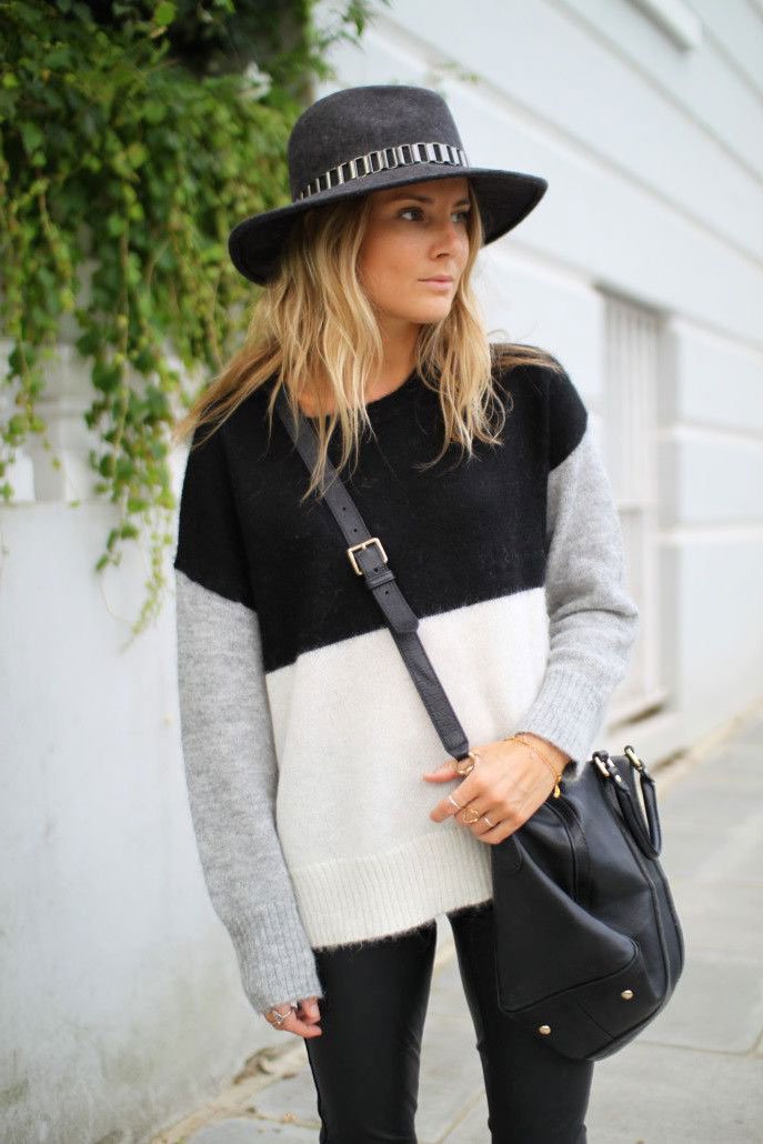 Street style look suéter preto e branco, calça preta e chapéu cinza.
