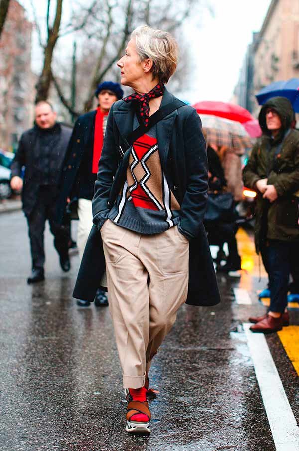 Street style look com suéter, maxi casaco, sandália, meia aparente e calça social.