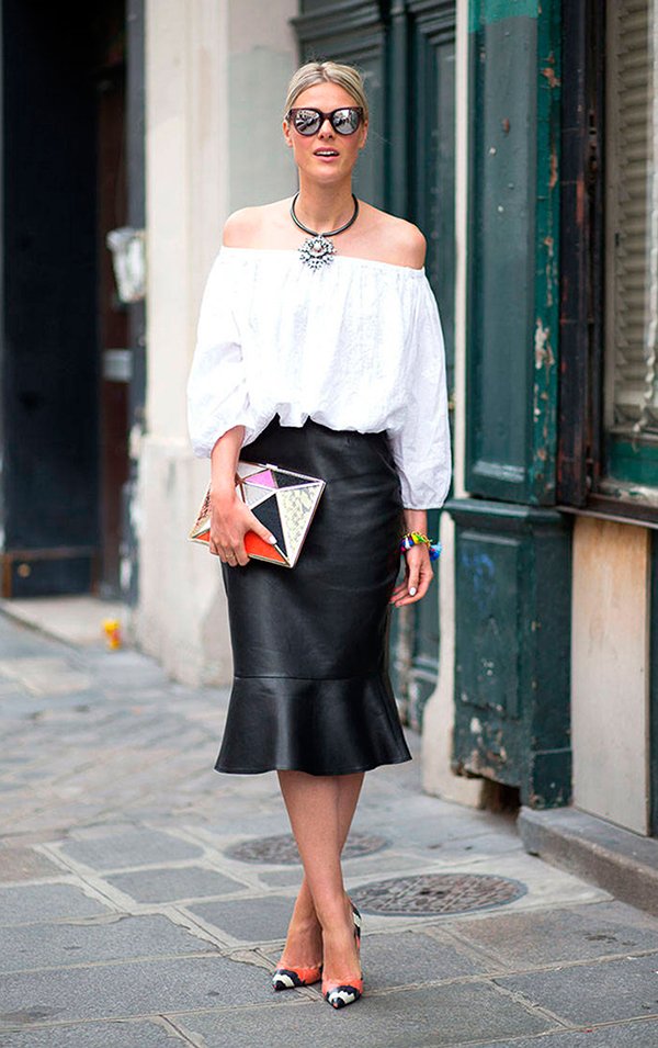 Foto de street style com blusa de ombros à mostra branca e saia midi de couro