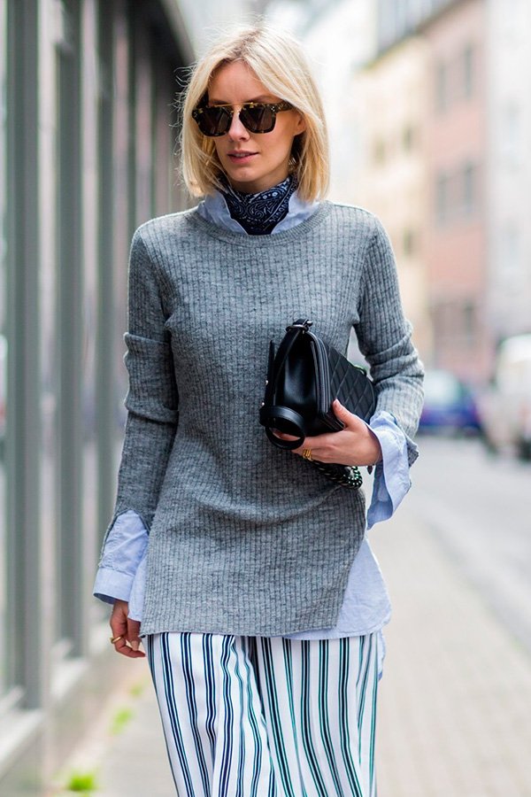 Street style look com blusa cinza, camisa azul e saia listrada.