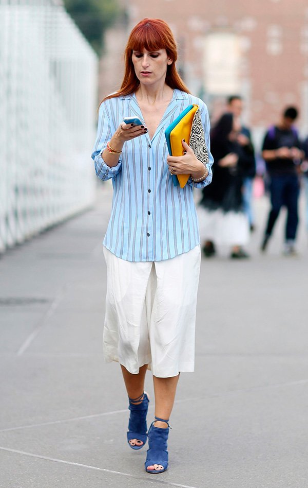 Street style look com camisa listrada, calça cropped, sapato azul e maxi clutch amarela.