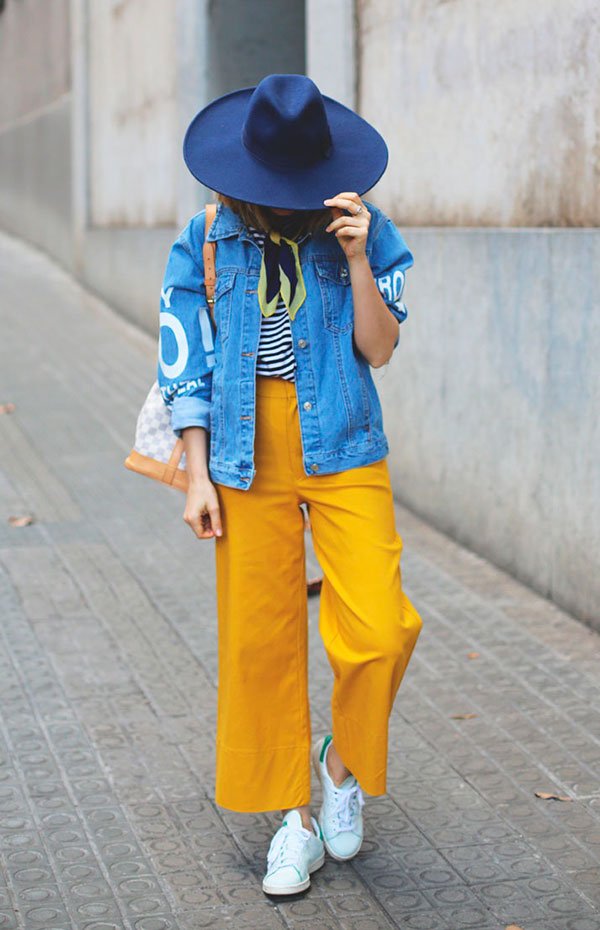 Street style look jaqueta jeans, blusa listrada, calça amarela e tênis branco.