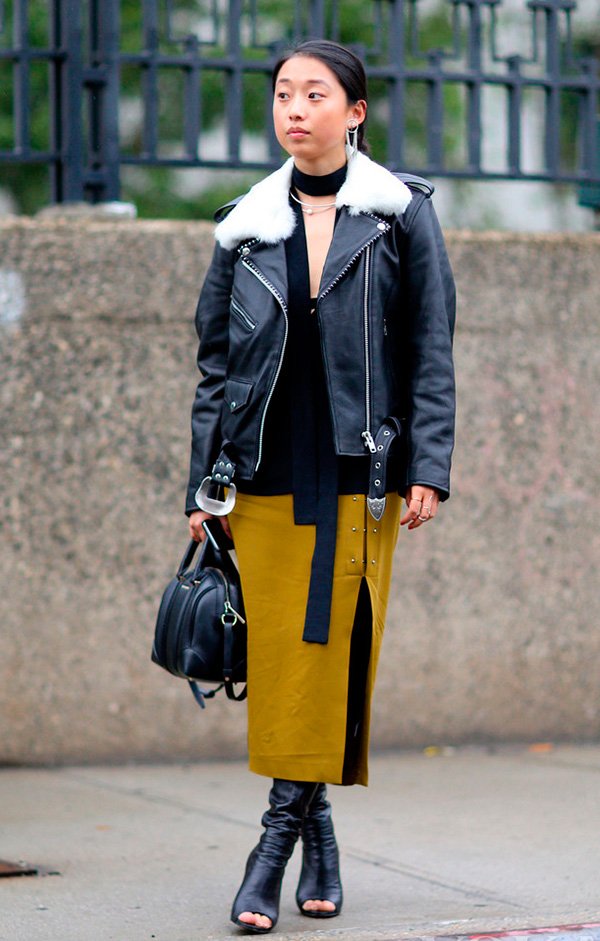 Street style look com jaqueta couro preta, skinny scarf, saia fenda e bota aberta.