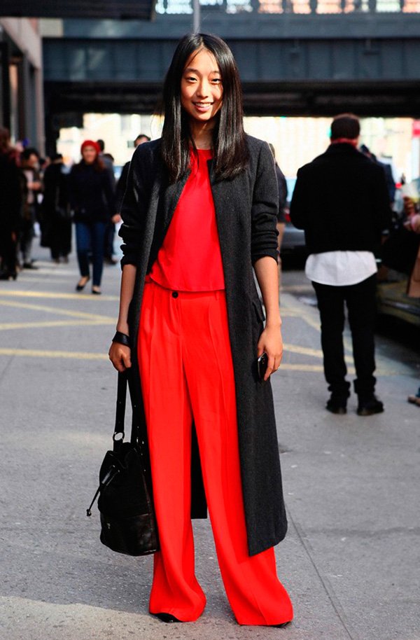 Street style look com macacão vermelho e maxi casaco preto.