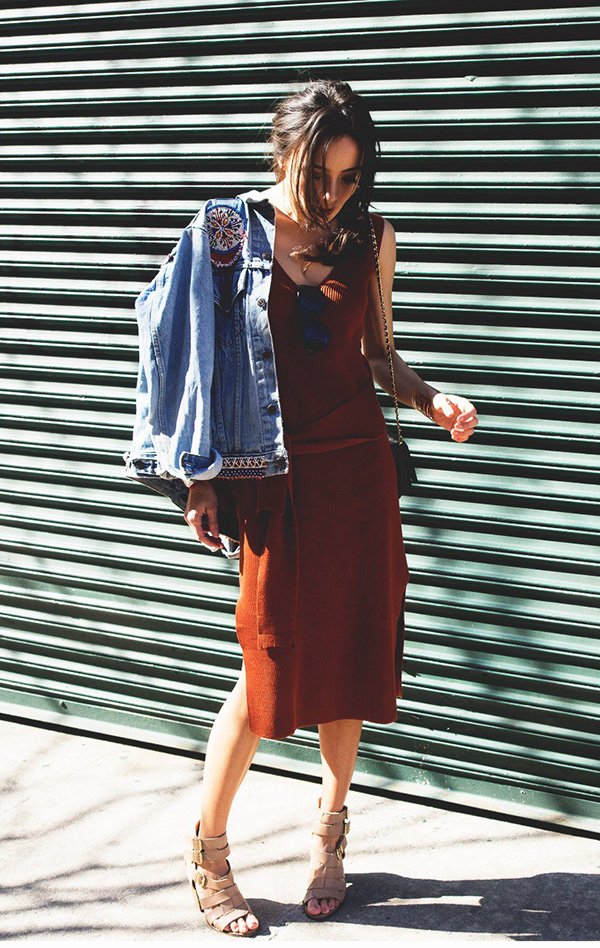 Street style look com vestido marrom, jaqueta jeans e sandália bege.