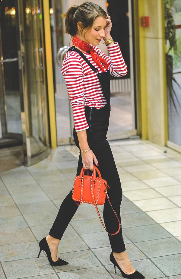 Street style look blusa listrada, macacão preto, bandana e bolsa vermelha.