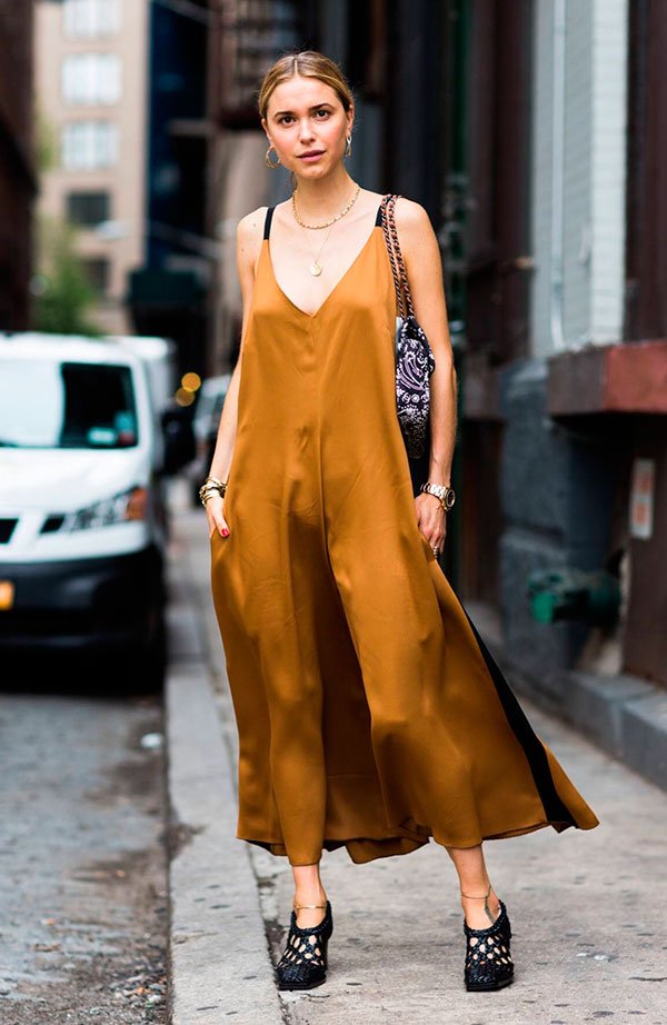 Pernille Teisbaek usa slip dress dourado com sapato mule preto e bolsa estampada