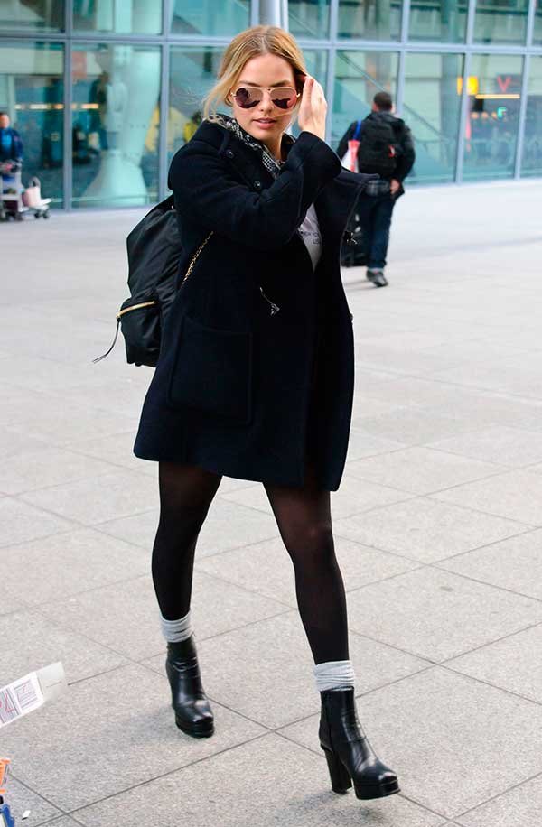Margot Robbie usa look total black com mochila e botas pretas