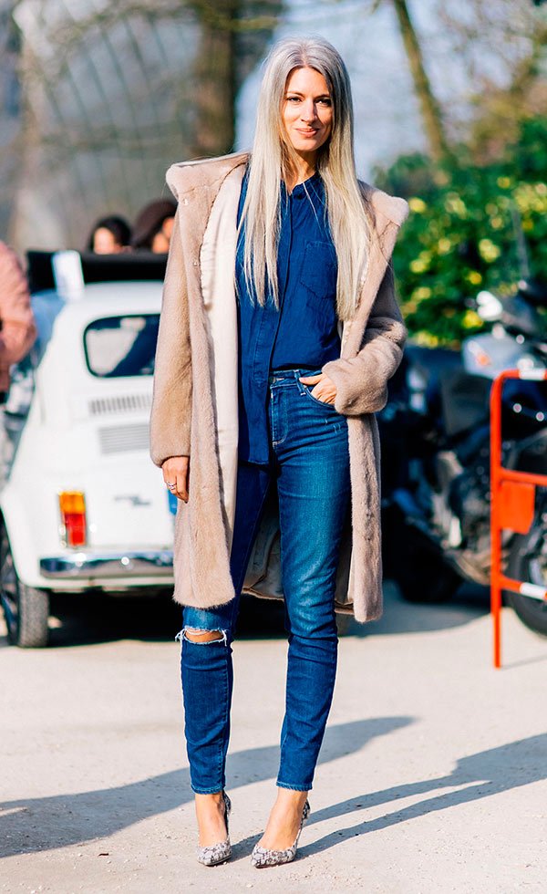 Street style look com camisa jeans e calça com casaco bege.
