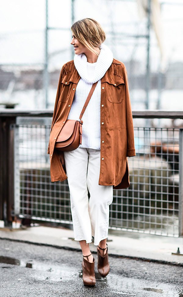 Street style look com blusa gola branca, calça jeans e casaco marrom.