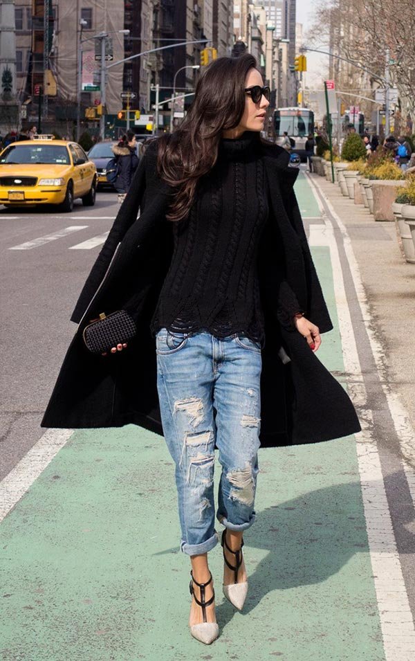 Street style look com blusa tricot preta, calça jeans e sobretudo.