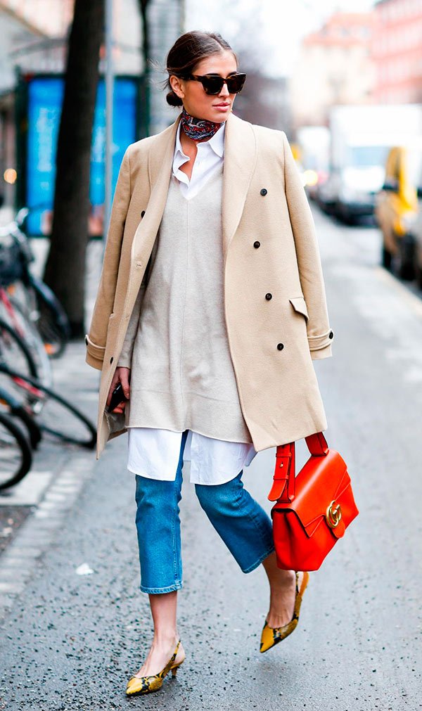 Street style look com casaco bege, camisa branca, e calça jeans.