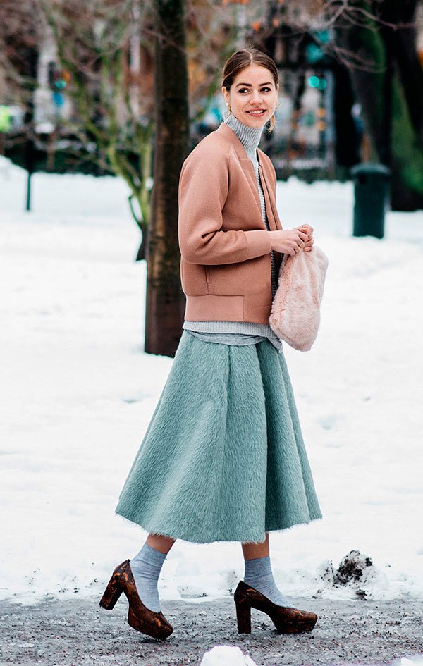 Street style look com casaco rosada, saia midi, sapato salto e meia aparente.