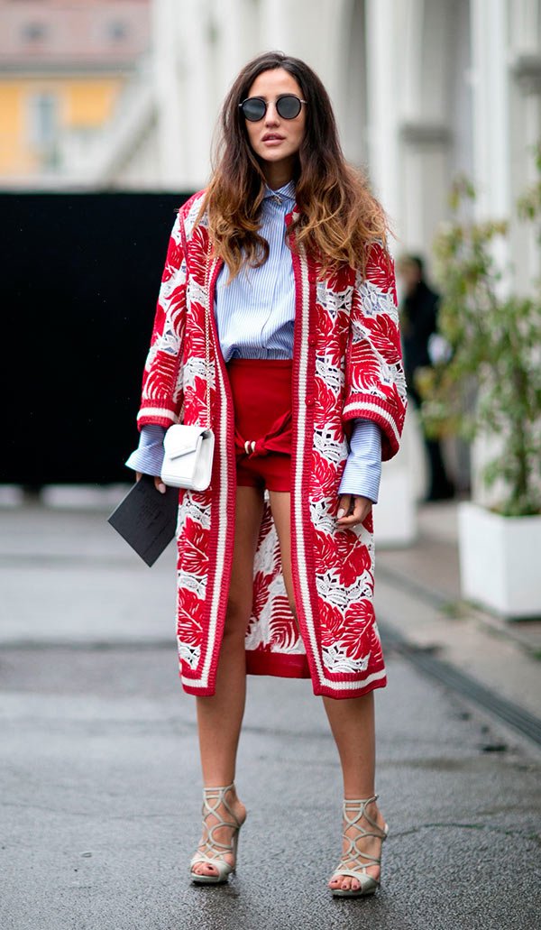 Street style look com camisa branca, casaco vermelho e shorts.