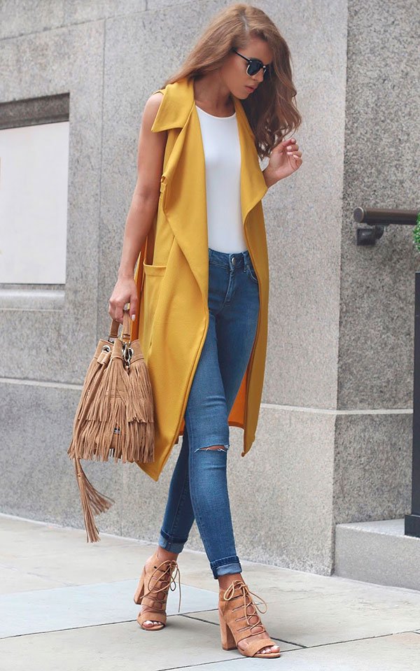 Street style look com colete amarelo e calça jeans.