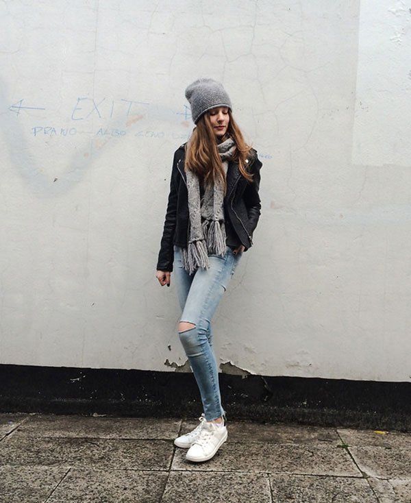 Street style look com jaqueta de couro preta, calça jeans e tênis branco.