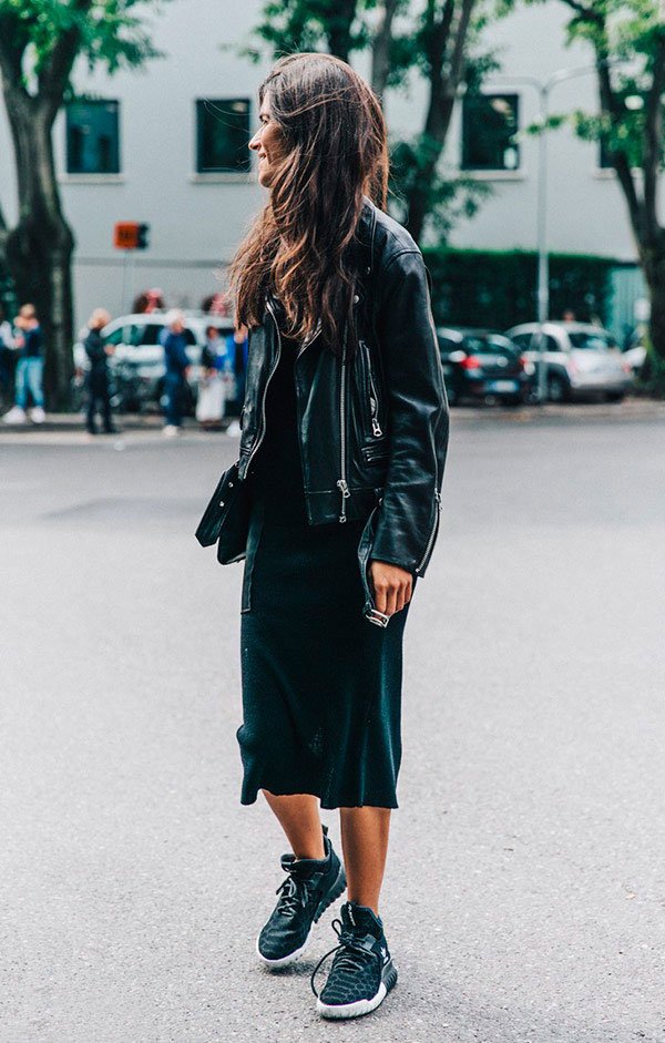 Street style look vestido preto, jaqueta couro preta e tênis.