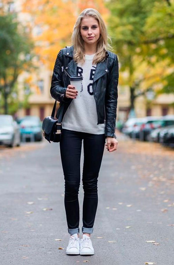 Street style look com jaqueta de couro preta, calça jeans e tênis.
