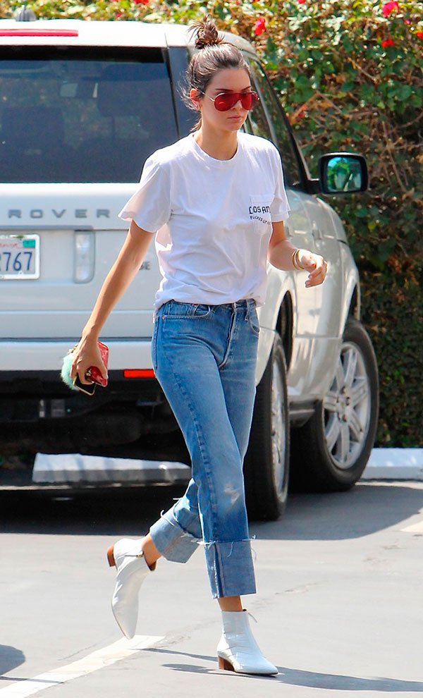 Street style look com camiseta, calça jeans e bota branca.