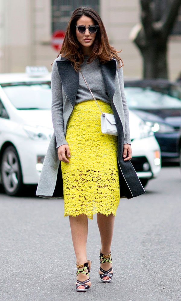 Street style look com casaco cinza e saia renda amarela.