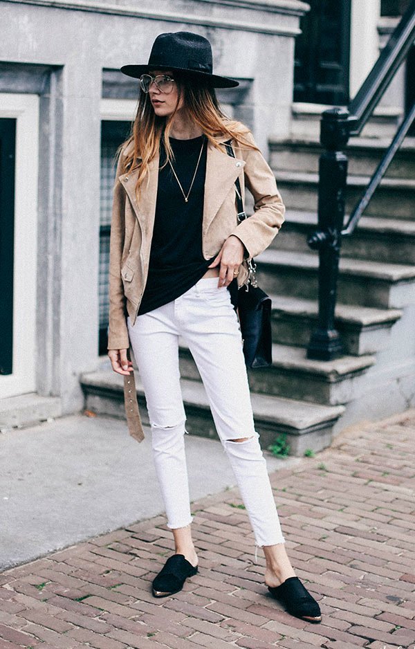 Street style look com blusa preta, casaco bege e calça jeans.