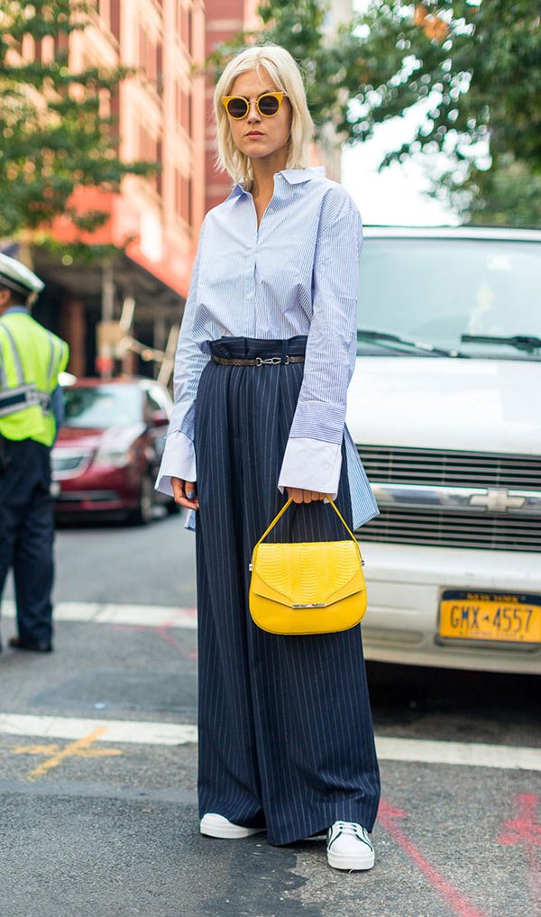 Street style lookc om camisa social, calça pantalona e bolsa amarela.