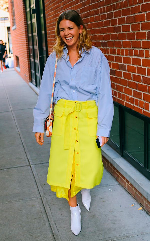 Street style look com camisa social e saia amarela.
