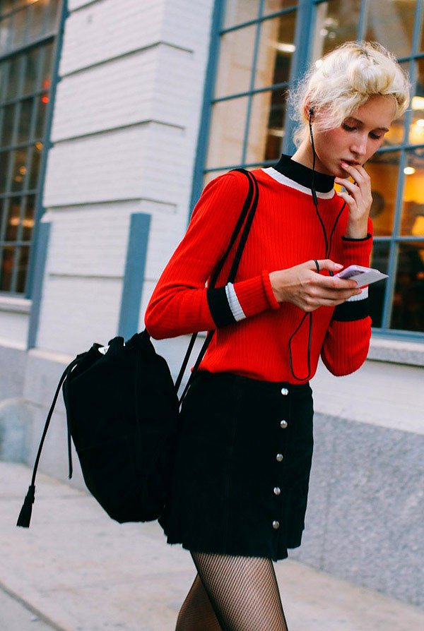 Street style look com suéter vermelho e saia botões.