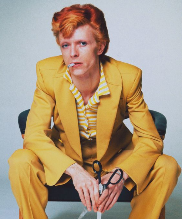 David Bowie - terno amarelo - CFDA Fashion Awards - Verão - sentada em uma cadeira - https://stealthelook.com.br