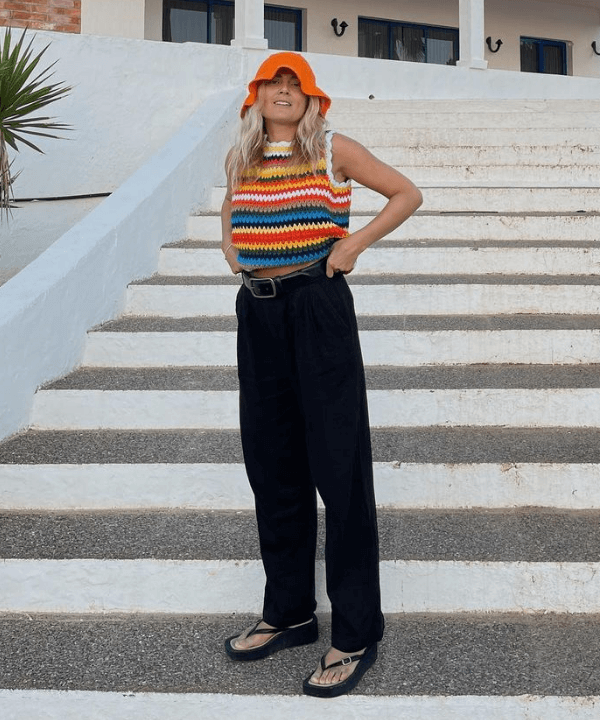 Lucy Williams - calça preta, chinelos, bucket hat e top de crochê - looks novos - verão - em pé na escada - https://stealthelook.com.br
